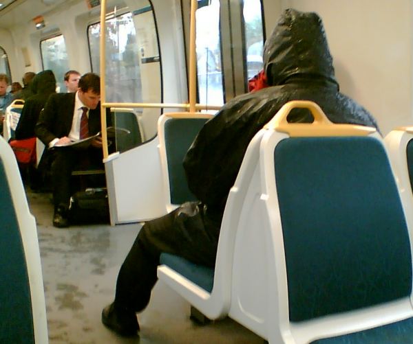 Man with wet coat sitting on on train